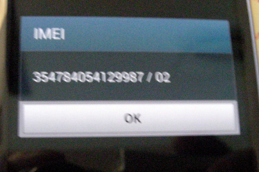 A phone screen showing the result of dialling star hash 06 hash: a dialog headed IMEI with the number 354784054129987 / 02 and an OK button.